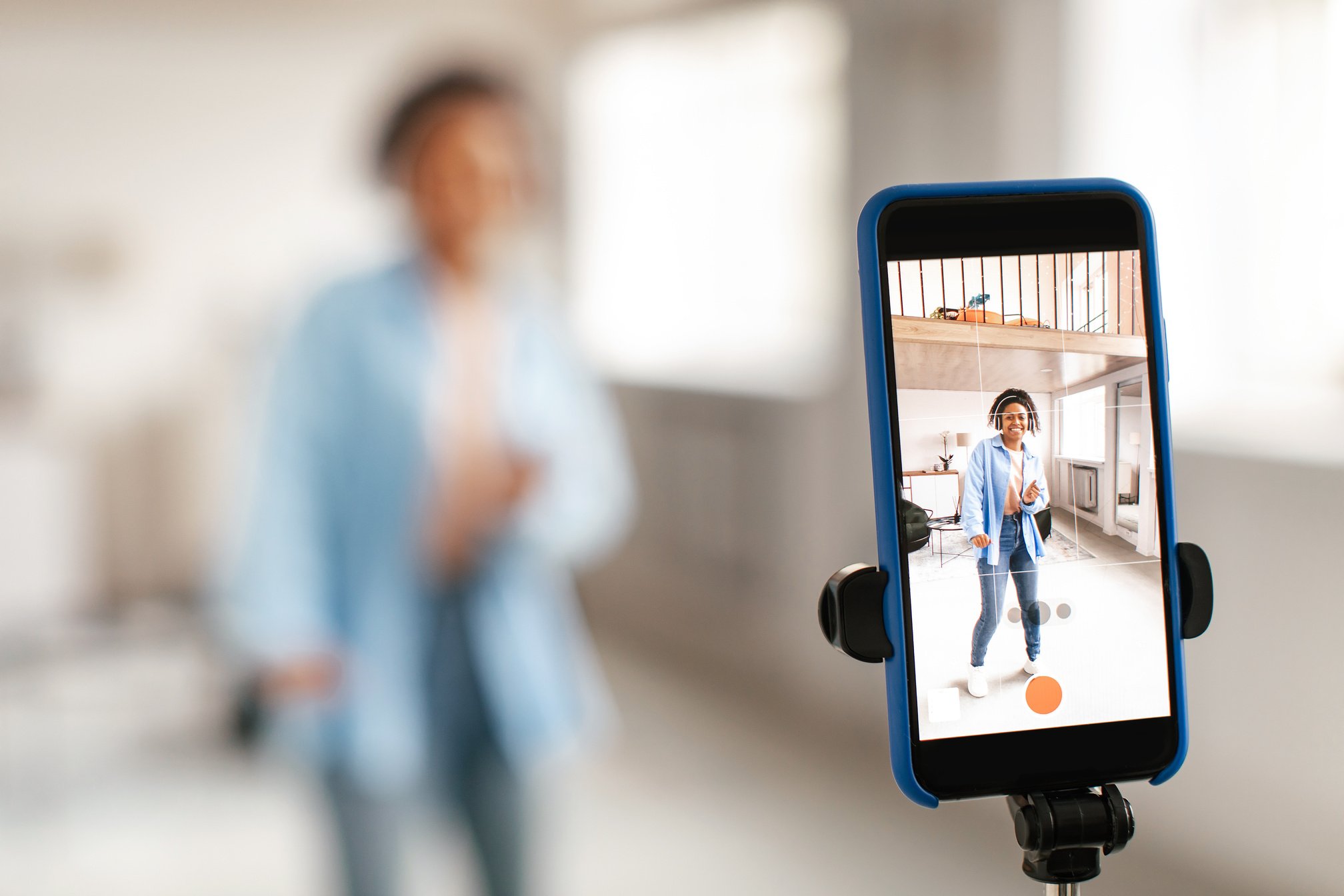 Cheerful black woman filming dance video on cell phone